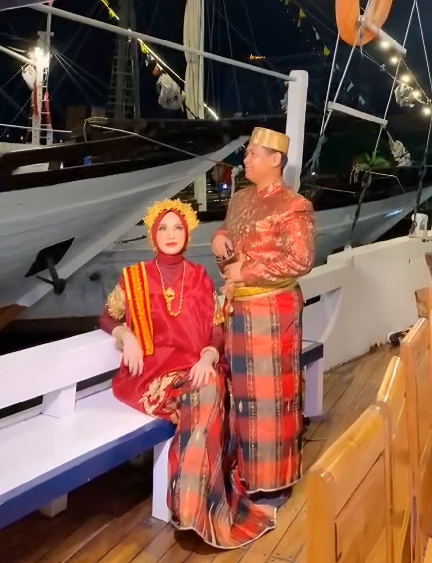 Pasangan pre-wedding berbaju adat Bugis-Makassar di dek kapal pada malam hari